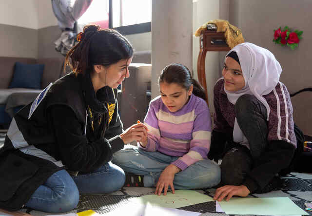 IRC Women’s Protection and Empowerment assistant Diana helps Ameera write her emotions on paper at one of IRC’s safe space sessions.